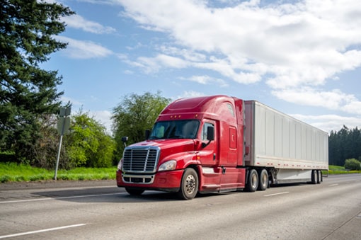Red semi-truck on highway over the road freight